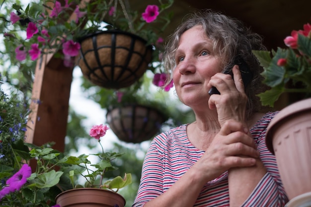 Mature woman calling on phone and looking at flowers