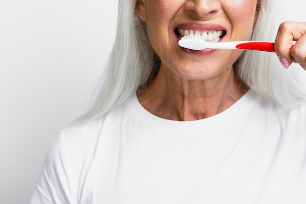 Photo mature woman cleaning her teeth