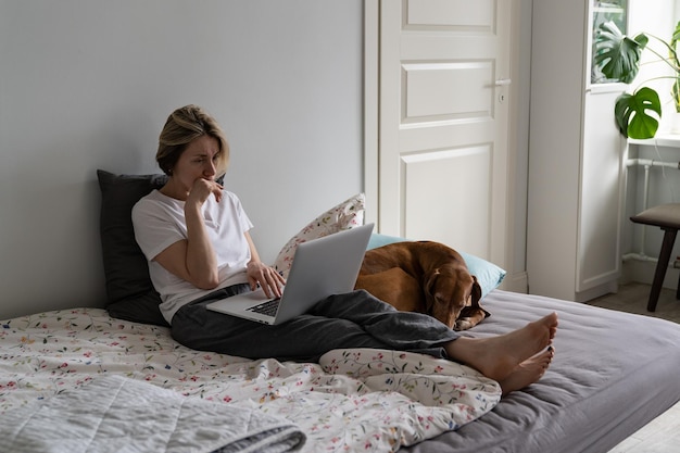 Mature woman finds job vacancy and thinks about writing worthy resume on laptop on bed