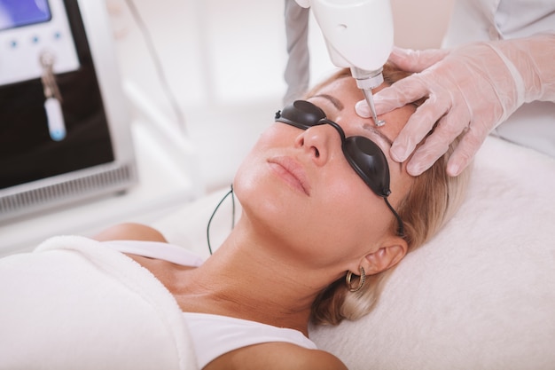 mature woman getting facial skincare treatment at beauty salon