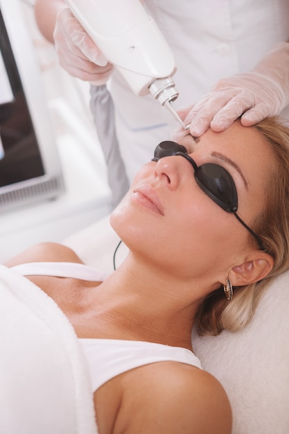 Mature woman getting facial skincare treatment at beauty salon