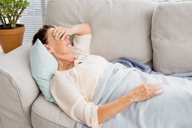 Mature woman having headache while lying on sofa