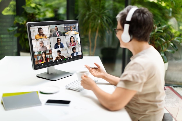 Mature woman having video call via computer in home office