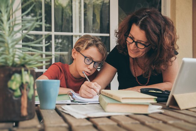 Photo mature woman helping son with studies at home