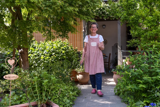 カメラを見ている彼女の家の庭の成熟した女性