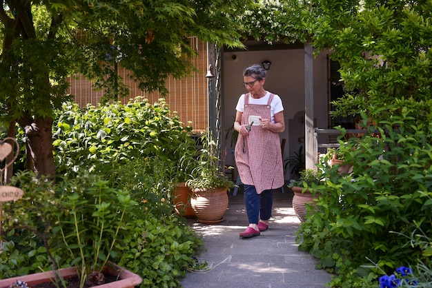 Mature woman in her home garden looking at the plants