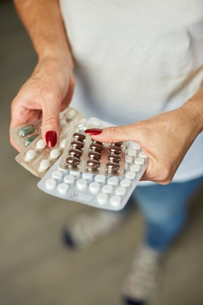 Mature woman hold in hand blister pack of pills