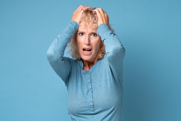 Photo mature woman holding head in hands feels unhealthy