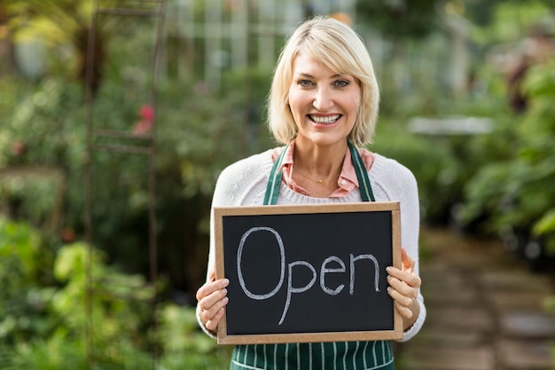 Mature woman holding open sign placard