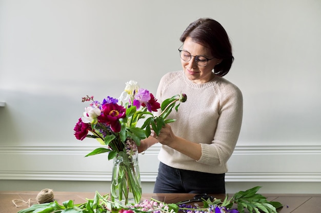 Donna matura a casa con fiori primaverili