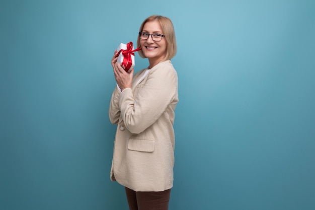 Mature woman in a jacket received a gift for the holiday on a studio background with copy space