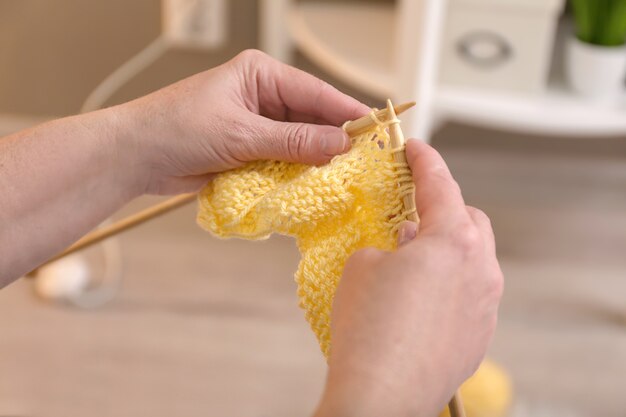 Mature woman knitting warm sweater, closeup