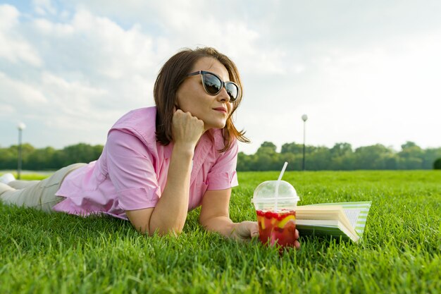 Mature woman lies on green grass