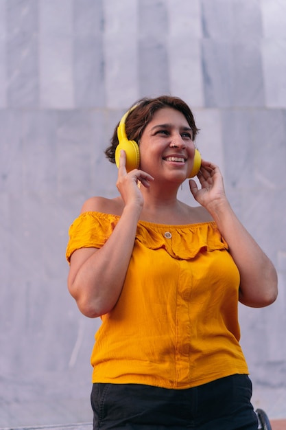 Mature woman listening to music with headphones on the street