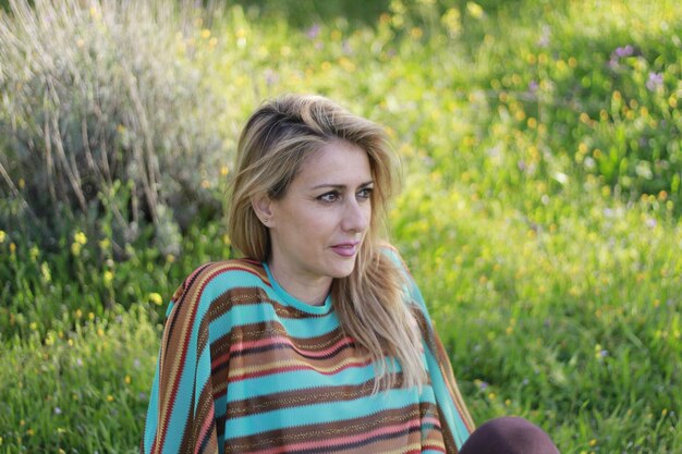 Photo mature woman looking away while sitting on field