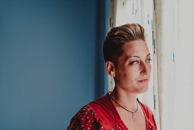 Photo mature woman looking away while standing by window at home