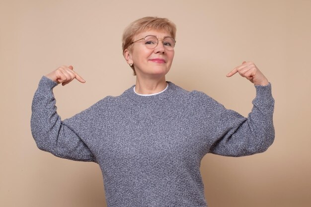 Mature woman looking confident with smile on face pointing oneself with fingers proud and happy