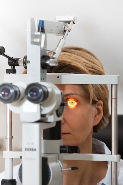 Photo mature woman looking through eye test equipment