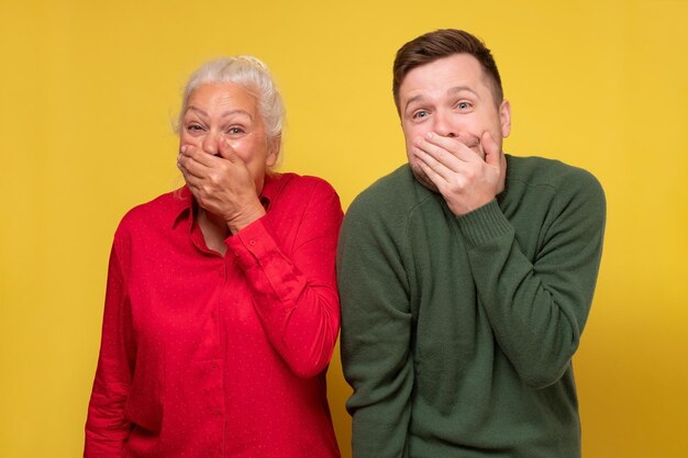 Mature woman and man giggling together covering their mouths with hands trying to be calm