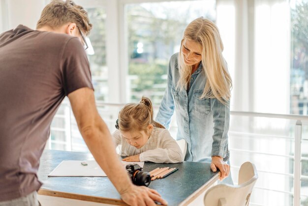 Mature woman and man looking at girl drawing at home