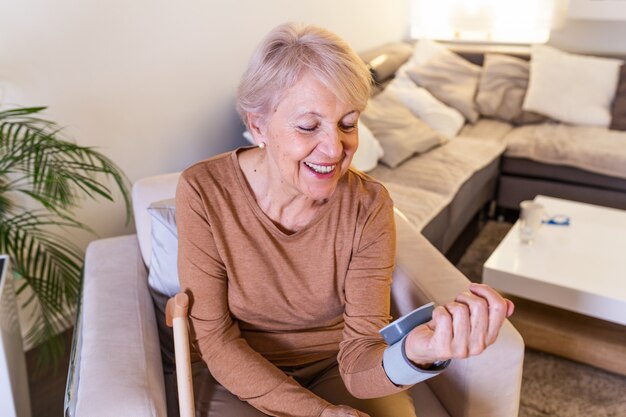 Mature woman measuring blood pressure at home. Senior woman checking blood presure at home