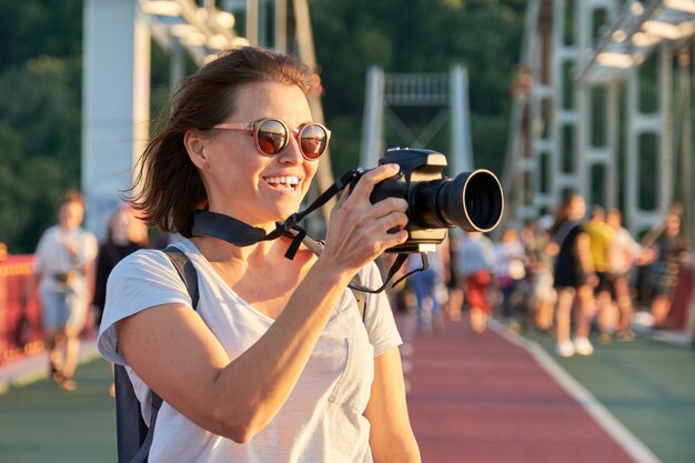 写真の写真を撮るカメラを持つ成熟した女性写真家