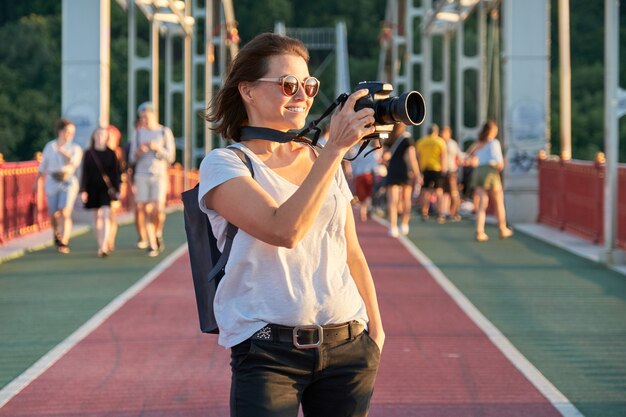 Mature woman photographing with camera. Woman photo journalist, travel blogger, middle-aged female hobby photo