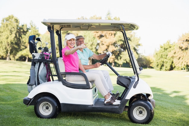 Mature woman pointing while sitting in golf buggy