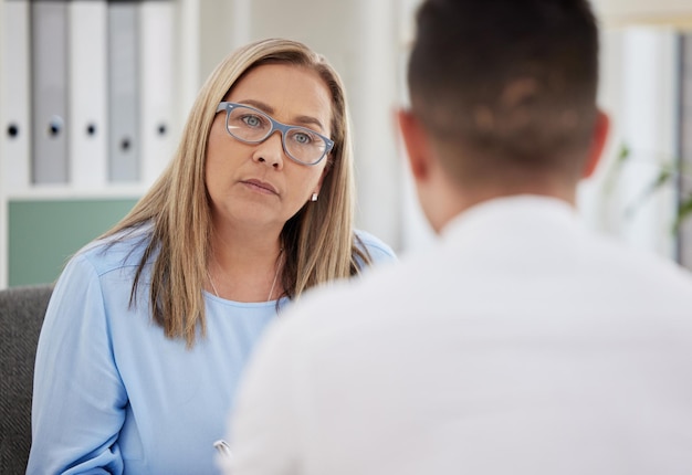 mature woman psychiatrist and patient talking during consultation in the clinic or psychologist listen to a man at the office mental health female therapist and conversation or guy for healing