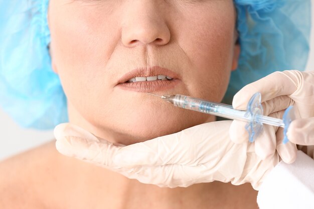 Mature woman receiving injection in face, closeup