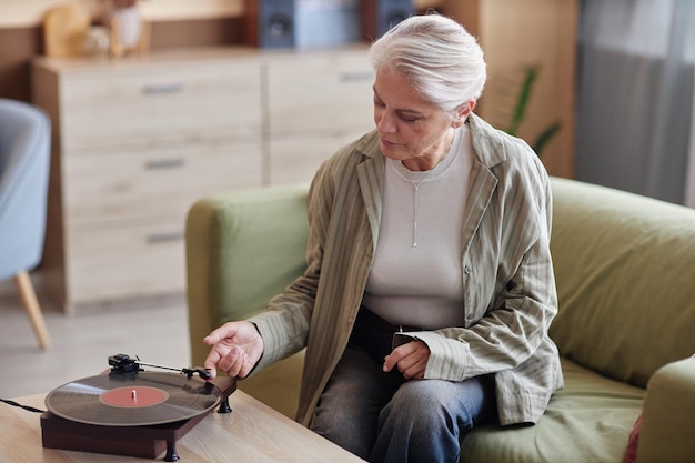 mature woman setting up retro record player at home