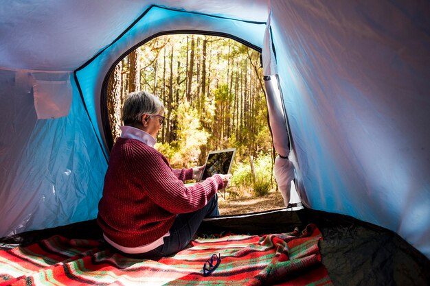 Mature woman sitting inside a tent in free wild camping