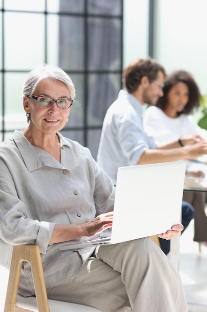 mature woman sitting with laptop looking at camera