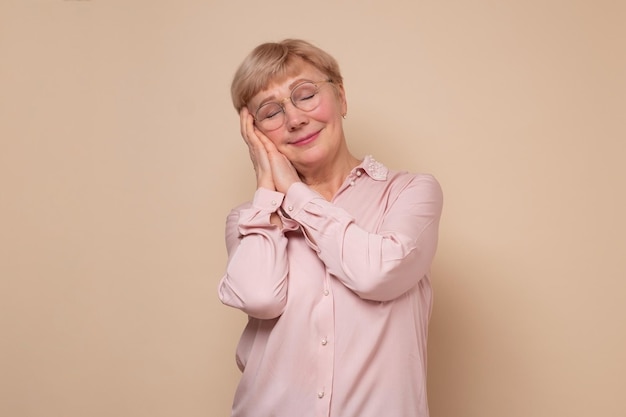 Mature woman sleeping tired dreaming and posing with hands together with closed eyes