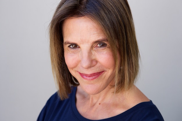 mature woman smiling against gray wall