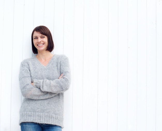 Mature woman smiling against white wall