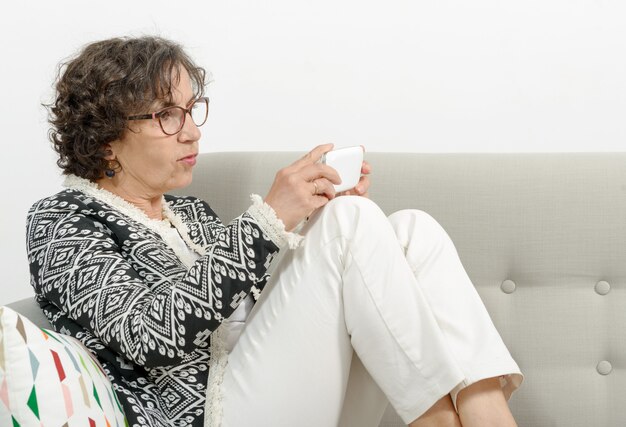 Mature woman on the sofa with a phone