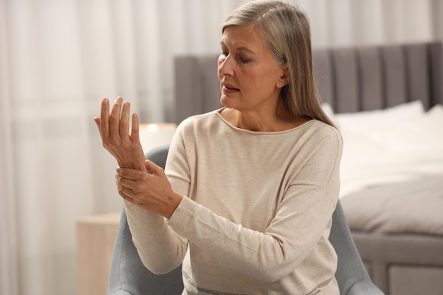 Mature woman suffering from pain in hand at home space for text Rheumatism symptom