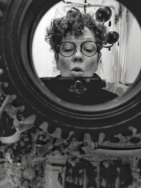 Foto donna matura che si fa un selfie con il cellulare riflettendosi nello specchio