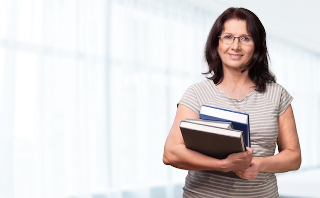 Mature woman teacher with books on background