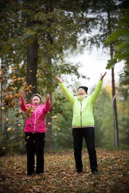 Mature woman throwing leaves into the air in an autumn park