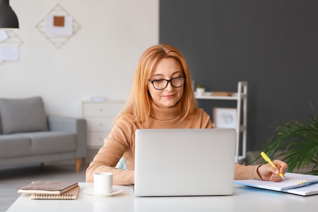 Donna matura che utilizza computer portatile per l'apprendimento in linea a casa