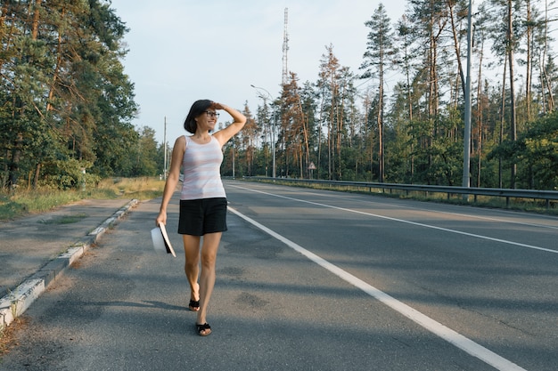 Mature woman walking along the road, looking at the road