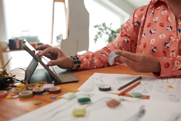 Photo mature woman watching tutorial on tablet computer when crafting at home