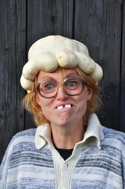 Photo mature woman wearing artificial pumpkin hat and making face