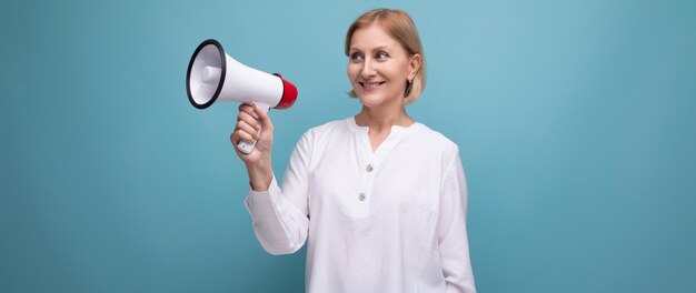 Mature woman with blond hairstyle speaks important news with loudspeaker