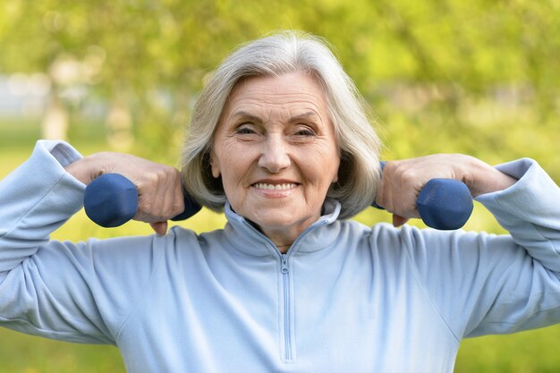 Mature woman with dumbbells in a park