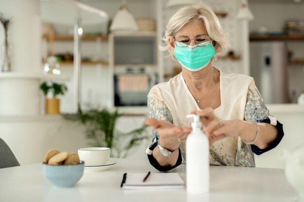코로나바이러스 전염병 동안 집에서 손을 소독하는 얼굴 마스크를 쓴 성숙한 여성