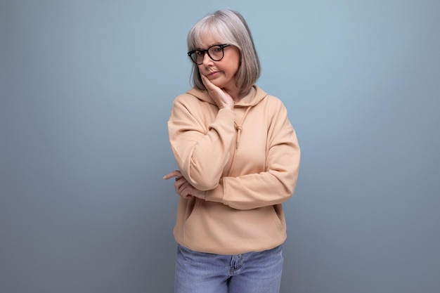 Mature woman with gray hair in casual look on studio background with copy space