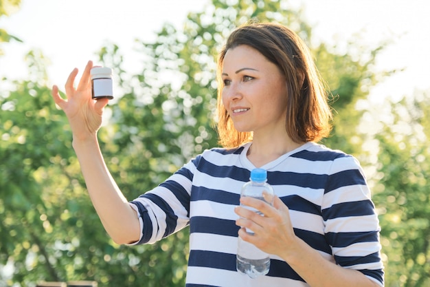 Mature woman with medication bottles of medicine, vitamins, supplements